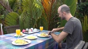 A man dining outdoors at a table with plates of food and drinks. - Houseboat Bee Kelotok (Kumai)