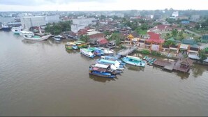 An aerial view of a riverside town with boats docked along the water. - Houseboat Bee Kelotok (Kumai)