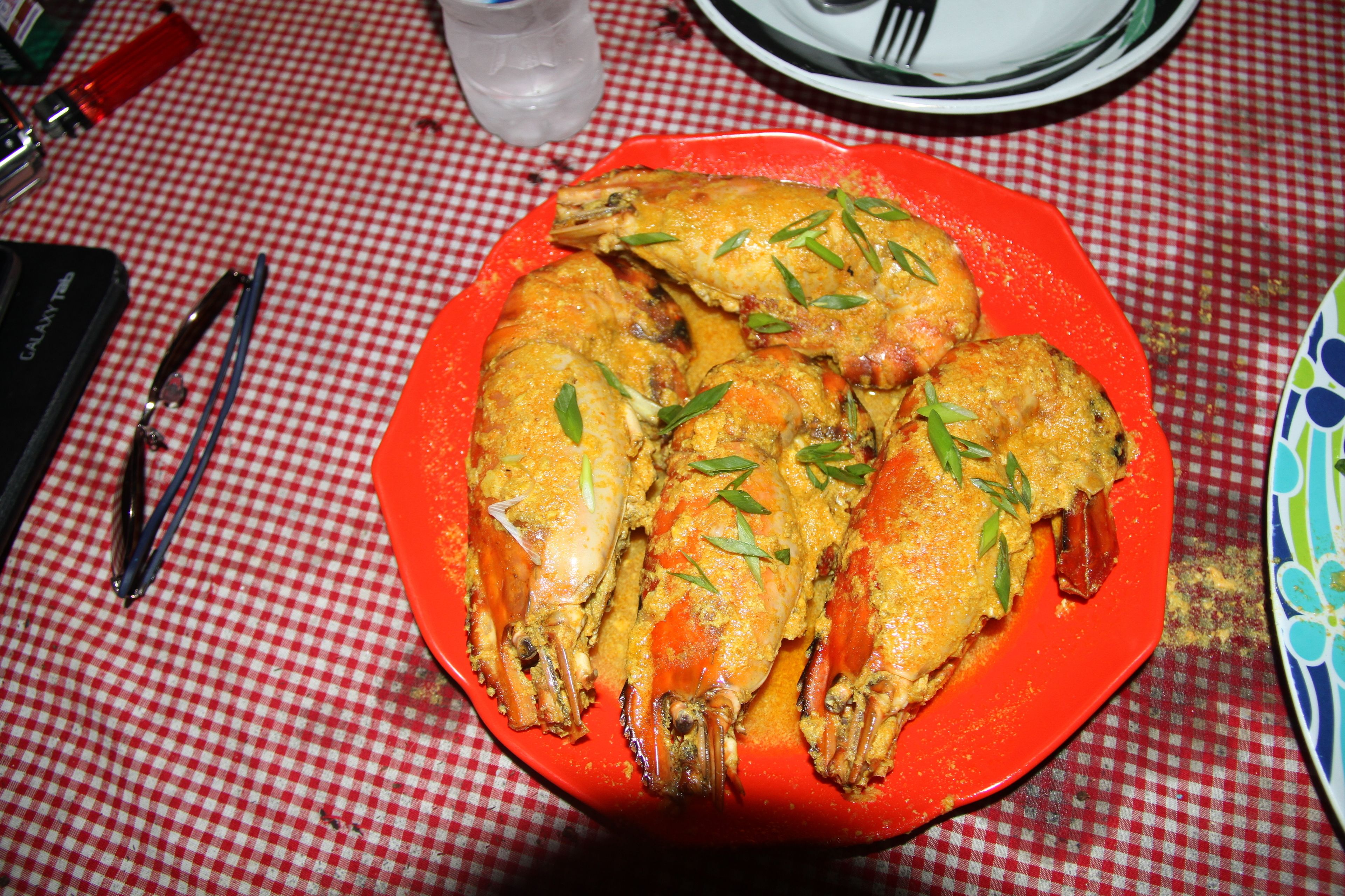 Une assiette rouge contenant des fruits de mer cuits, posée sur une nappe à carreaux.