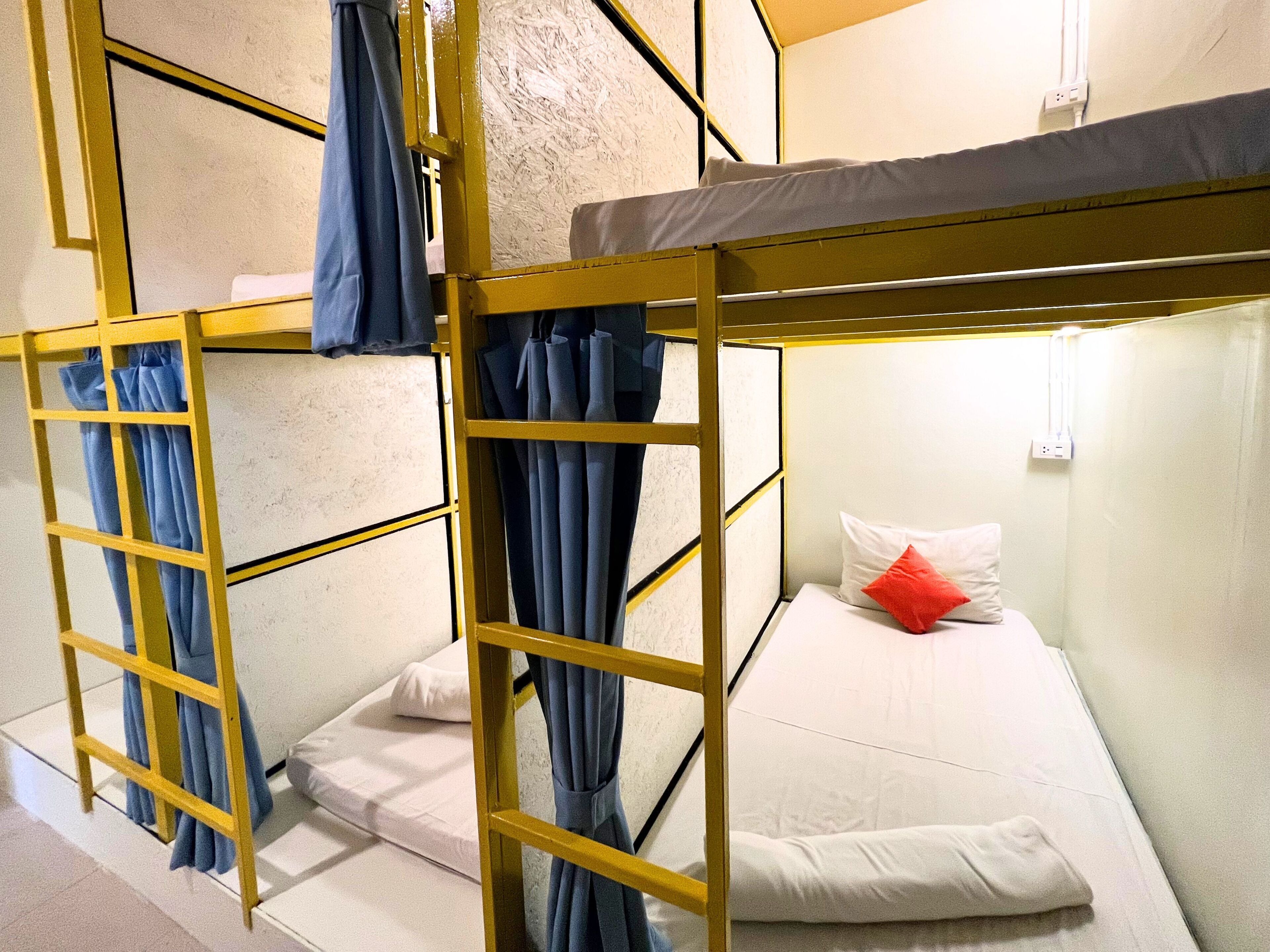 A bunk bed with a yellow frame, white bedding, and blue curtains.