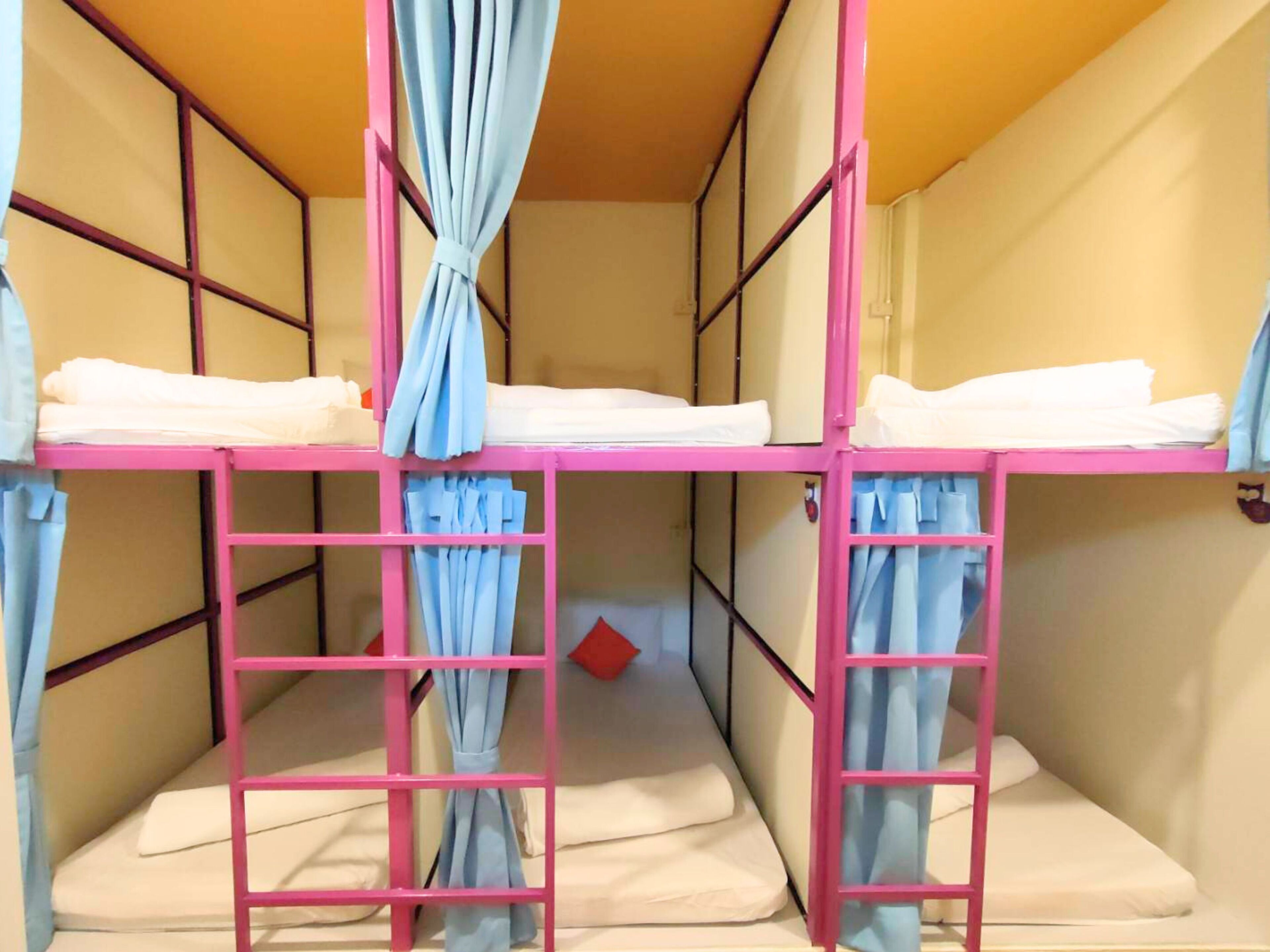 Habitación con literas, barandillas rosadas y cortinas azules.