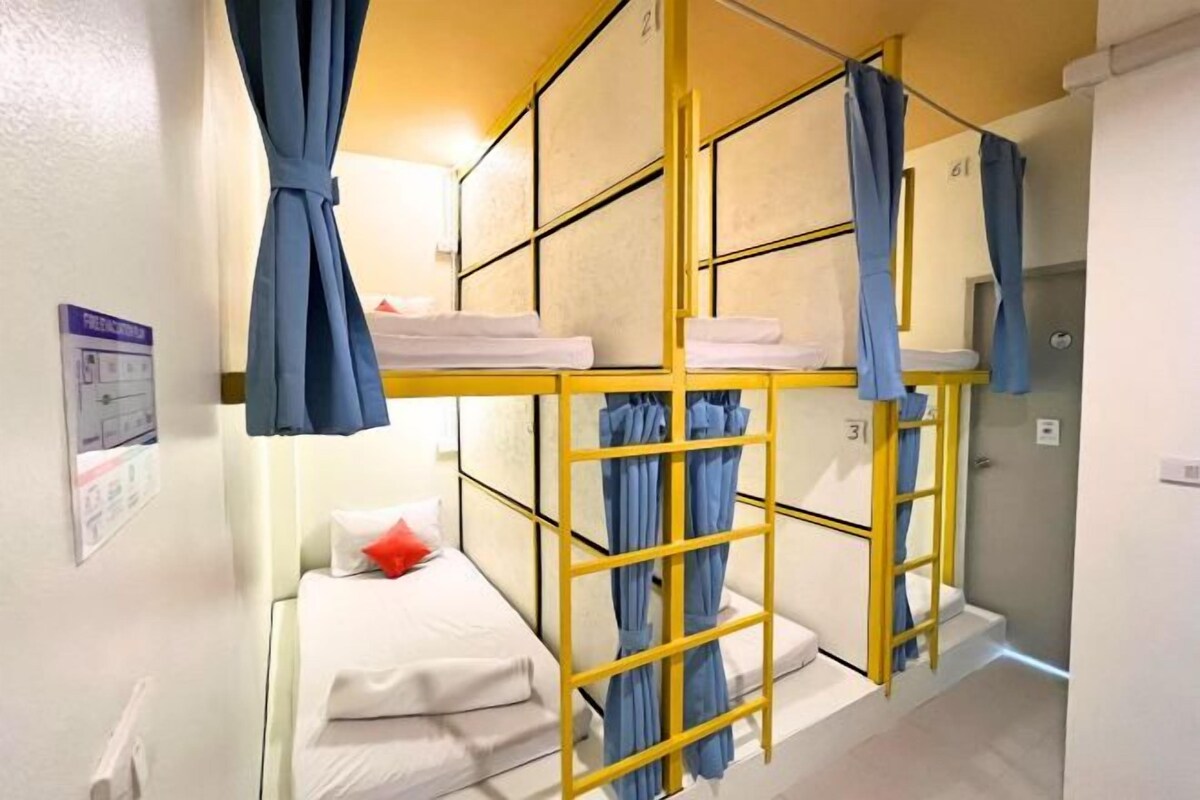 A bunk bed room with a yellow ladder, white bedding, and blue curtains.