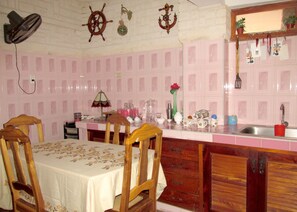 A kitchen with pink tiled walls, wooden cabinets, and a dining table with chairs. - Casa Salome (Viñales)