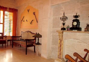 A room with a wooden bed, a small table with a lamp, a wall clock, and a chandelier. - Casa Salome (Viñales)
