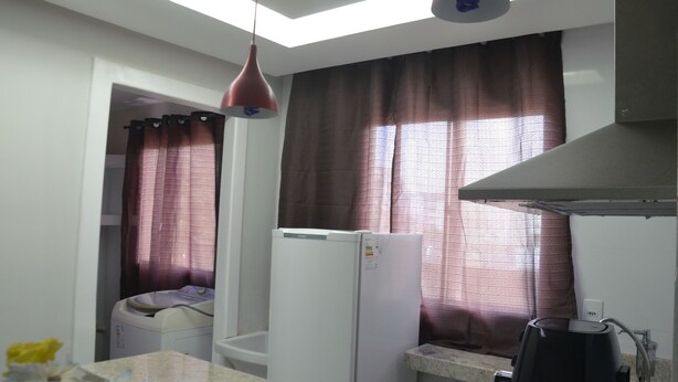 Una cocina compacta con refrigerador, cafetera y lavadora.