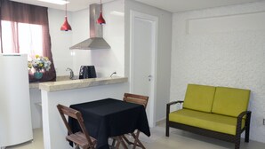 Un espacio habitable pequeño con kitchenette, mesa de comedor y sofá.
