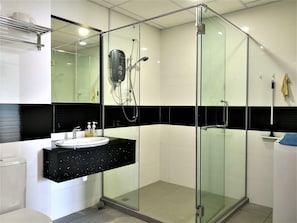 Un baño moderno con ducha de vidrio, lavamanos con encimera negra y espejo arriba.