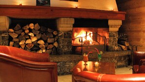 Un rincón acogedor con chimenea de piedra, leña apilada y asientos de cuero.