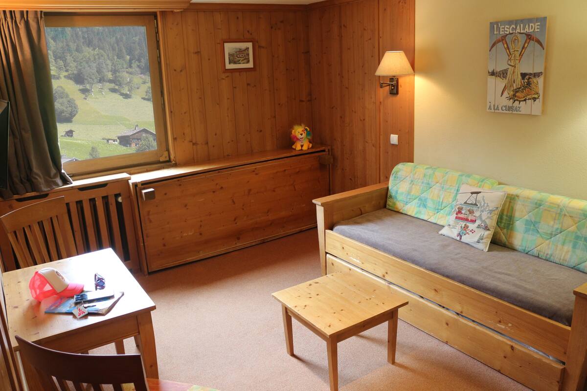 Una habitación acogedora con un banco de madera, una mesita pequeña y un sofá con funda acolchada.