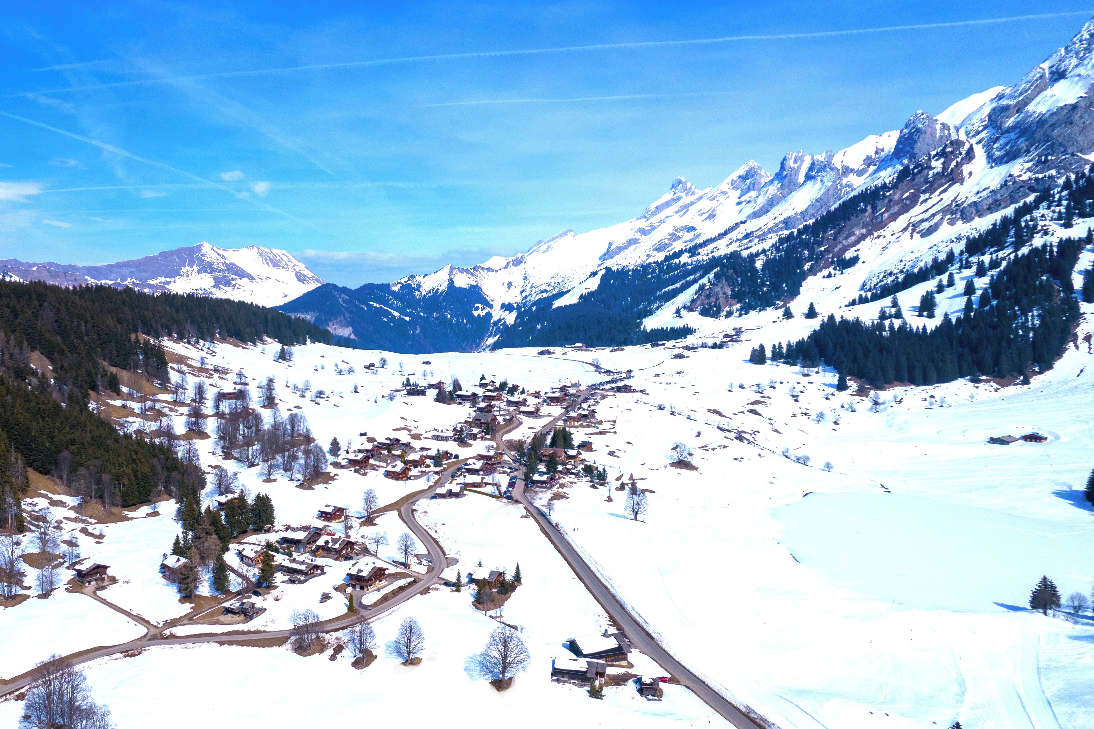 A snow-covered mountain village with a winding road and buildings scattered across the landscape.