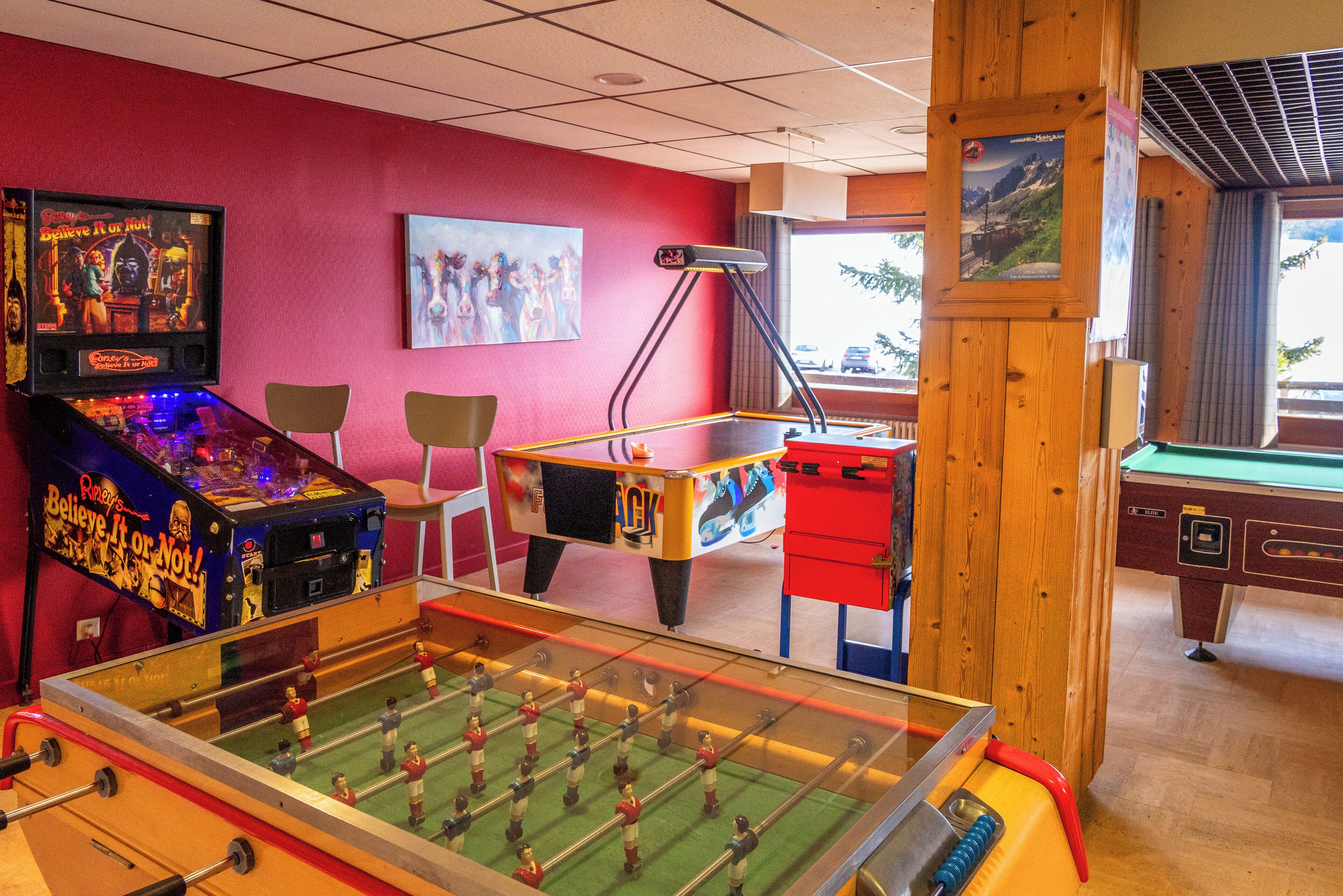 Ett rum med ett bordfotbollsspel, ett biljardbord och en bordsfotbollsmaskin.