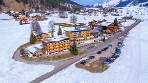 Un pueblo cubierto de nieve con un edificio anaranjado destacado, probablemente un hotel, que cuenta con varios pisos y balcones.