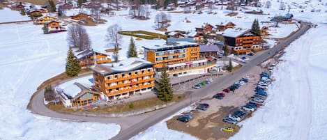 En snötäckt stad med en framträdande orangefärgad byggnad, troligen ett hotell, med flera våningar och balkonger.