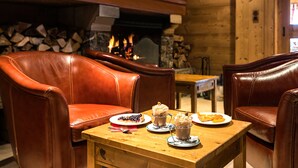 Un comedor acogedor con sillones de cuero, una mesa de madera y una chimenea con leña.