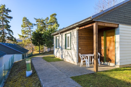 A single-story building with a covered patio area, a small table and chairs, and a wooden door.