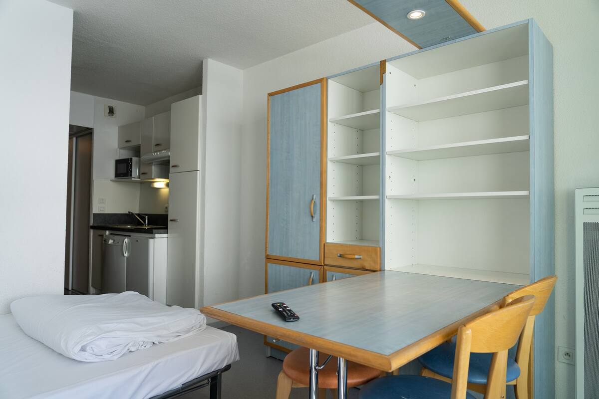 A compact room with a bed, a table, and a kitchenette.