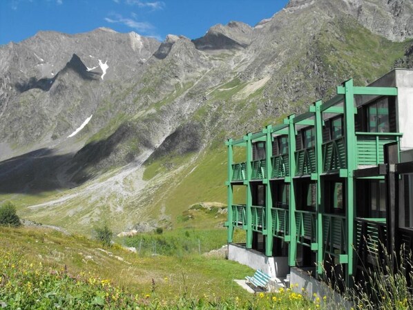 A mountain lodge with a green exterior and multiple windows, set against a backdrop of rugged mountains and a clear sky. - Residence Azureva Piau-Engaly (Aragnouet)