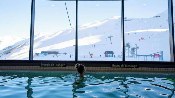 Una piscina con vistas a una montaña nevada y pistas de esquí.