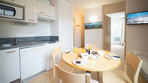 Una cocina moderna con armarios blancos, lavavajillas y un comedor con una mesa redonda y sillas.