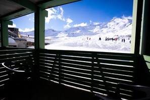 A view from a covered area with a wooden slatted roof, overlooking a snowy mountain landscape with skiers and a ski lift in the distance. - Residence Azureva Piau-Engaly (Aragnouet)