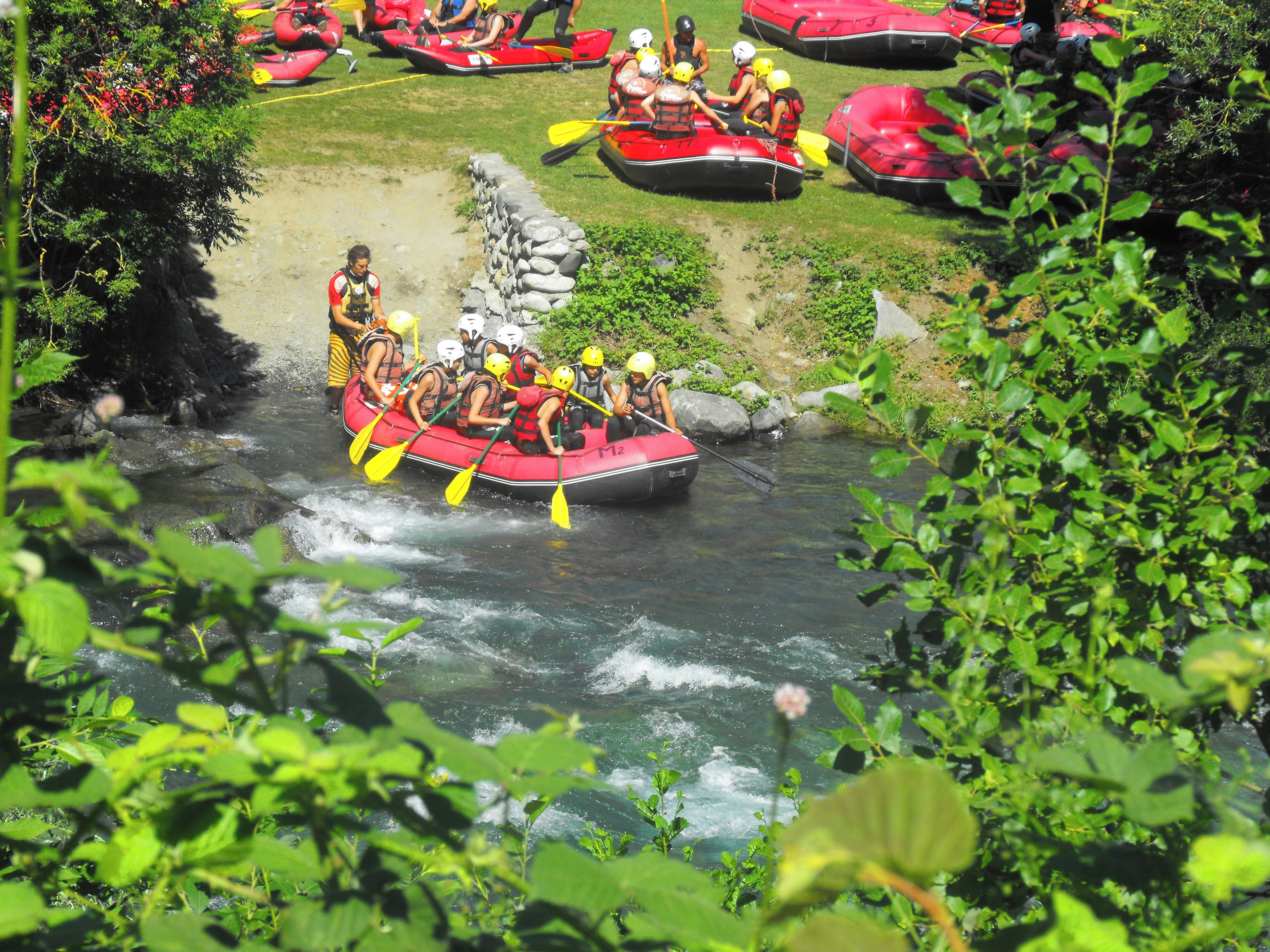 Un grupo de personas en balsas rojas navegando un río rodeado de vegetación.