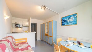 Un espacio habitable compacto con kitchenette, comedor y dormitorio.