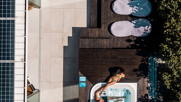 An aerial view of a rooftop pool area with a hot tub, wooden deck, and solar panels. - Alkamuri Posh Hotel & Spa (Alcamo)