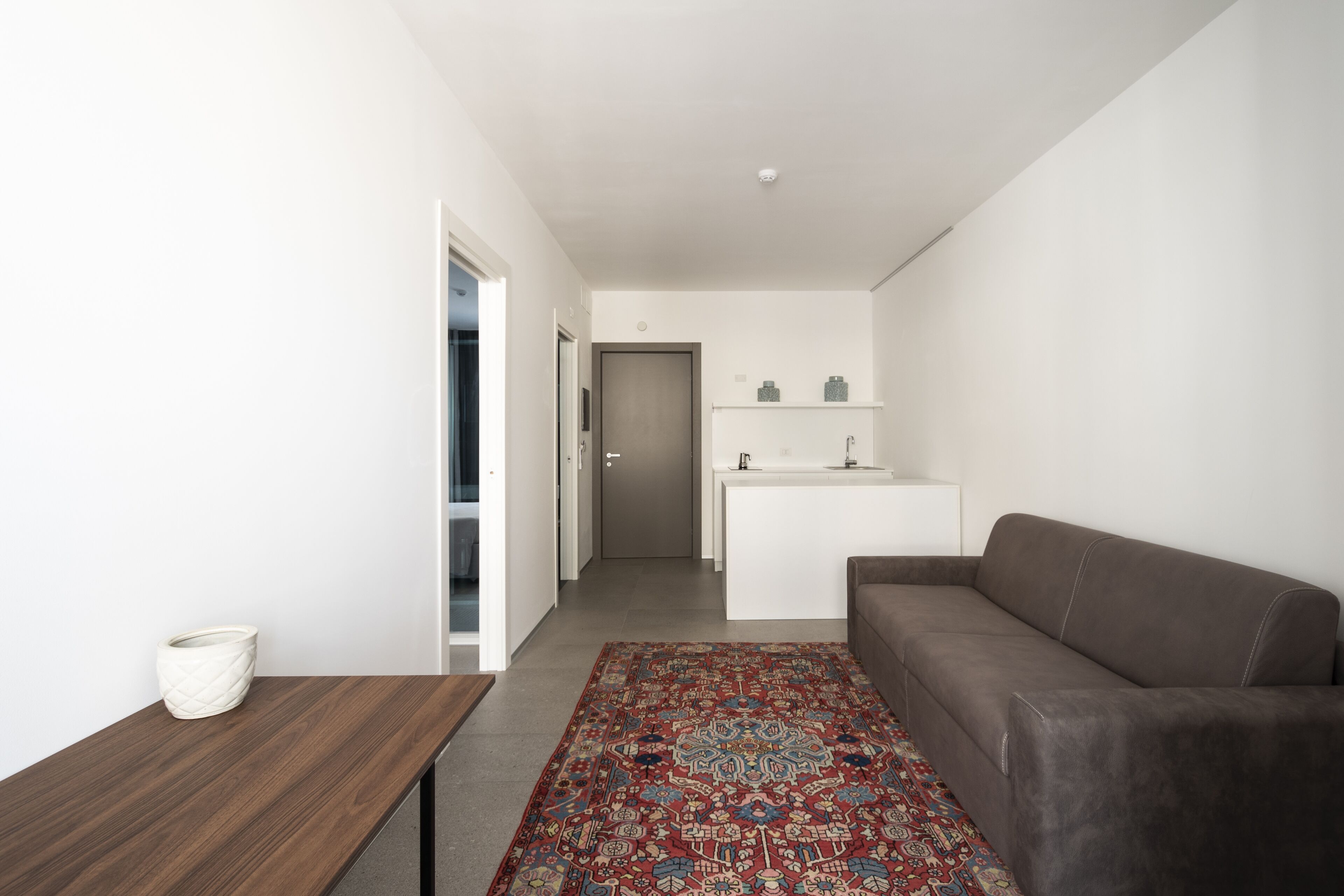 A modern living room with a brown sofa, a wooden side table, and a patterned rug.