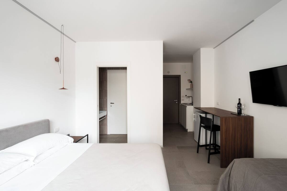 A modern hotel room with a bed, a desk, and a TV.
