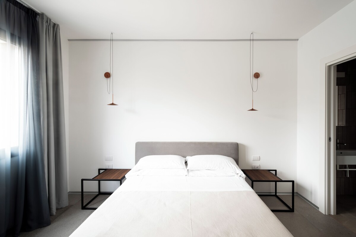 A modern hotel room with a large bed, bedside tables, and a neutral color scheme.