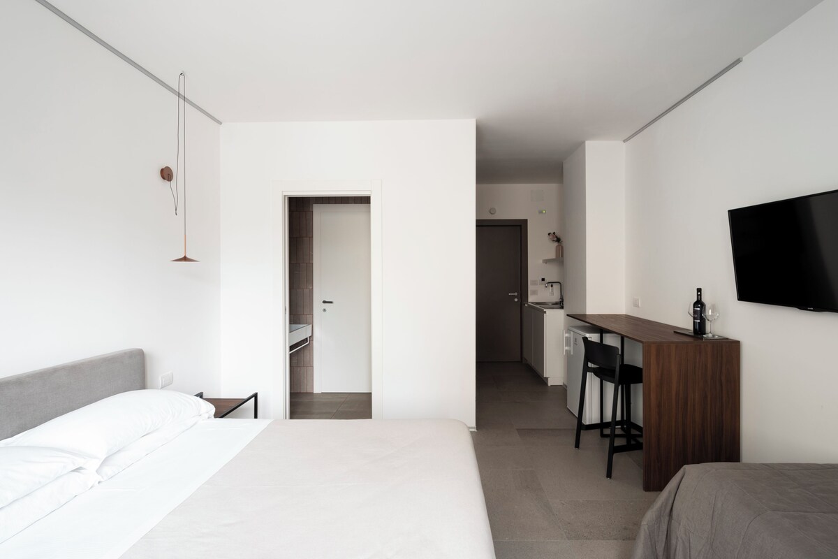 A modern hotel room with a bed, a desk, and a TV.