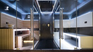 A modern sauna with glass walls, wooden benches, and a central heating element. - Alkamuri Posh Hotel & Spa (Alcamo)