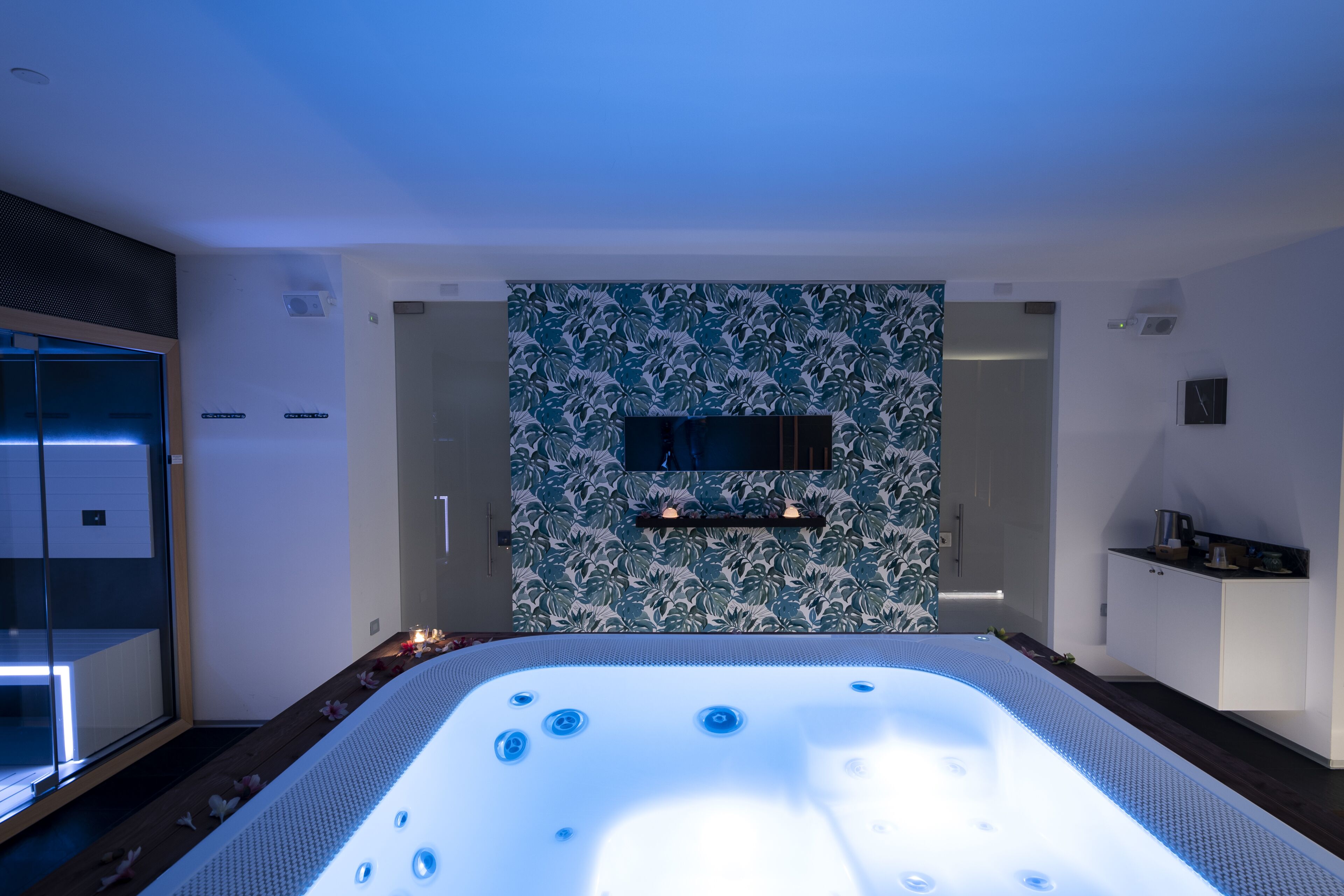 A modern bathroom with a large bathtub, a shower area, and a wall with a floral pattern.