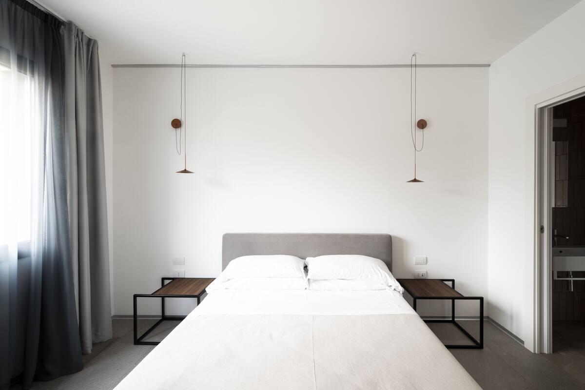 A modern hotel room with a large bed, bedside tables, and a neutral color scheme.