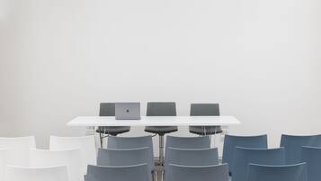 A conference room with a white table, grey chairs, and a laptop on the table.