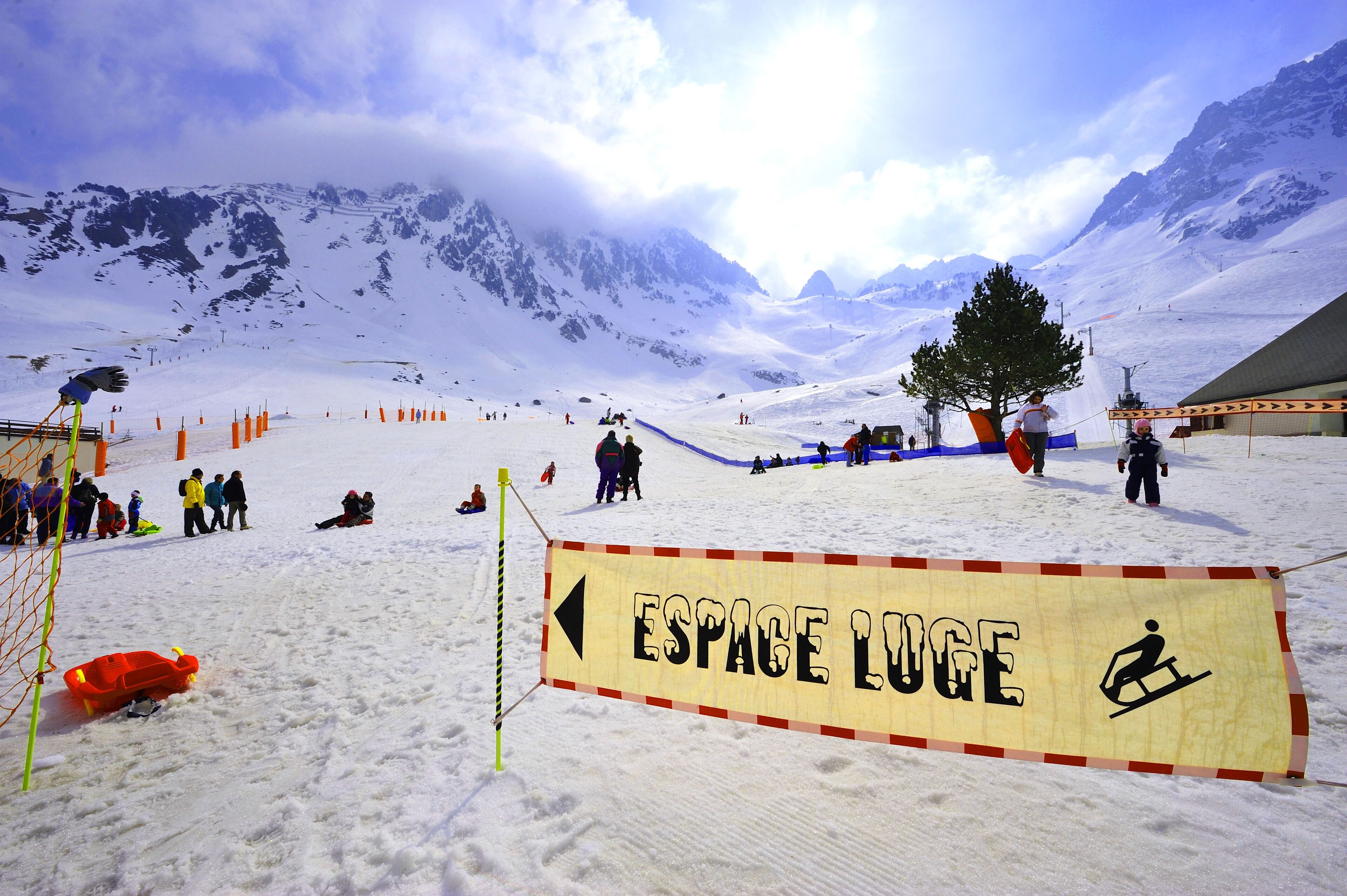 A snowy mountain area with a sign reading "ESPACE LUGE" and a sled.