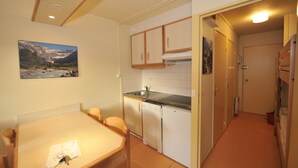 Une cuisine de taille réduite comprenant une table à manger, des placards et un réfrigérateur.