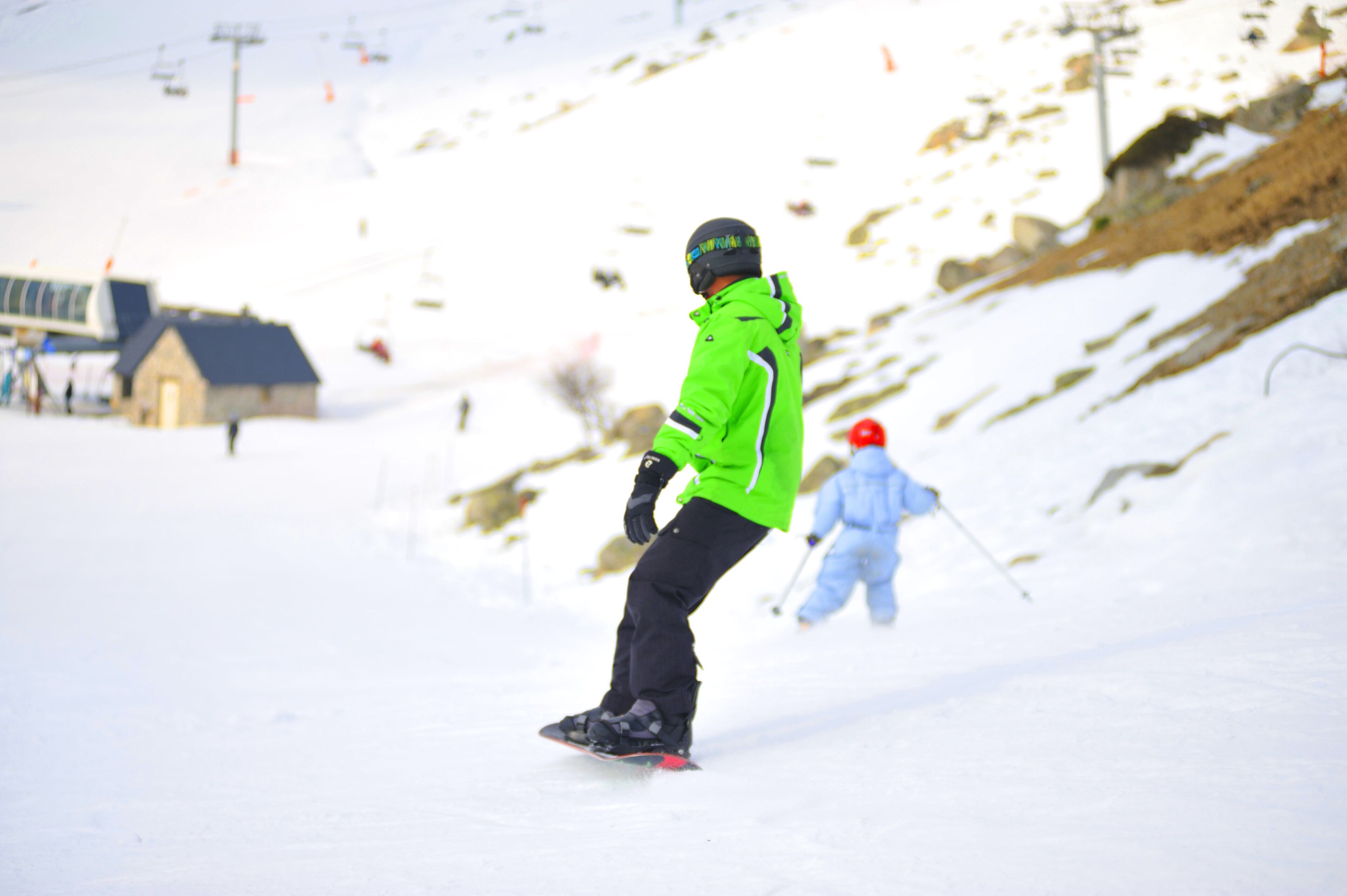 A person snowboarding on a snowy slope with a ski lift in the background.