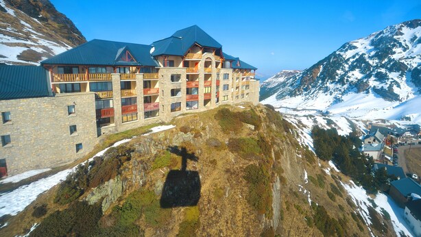 Un hôtel à plusieurs étages, doté de balcons et situé dans un cadre montagneux.