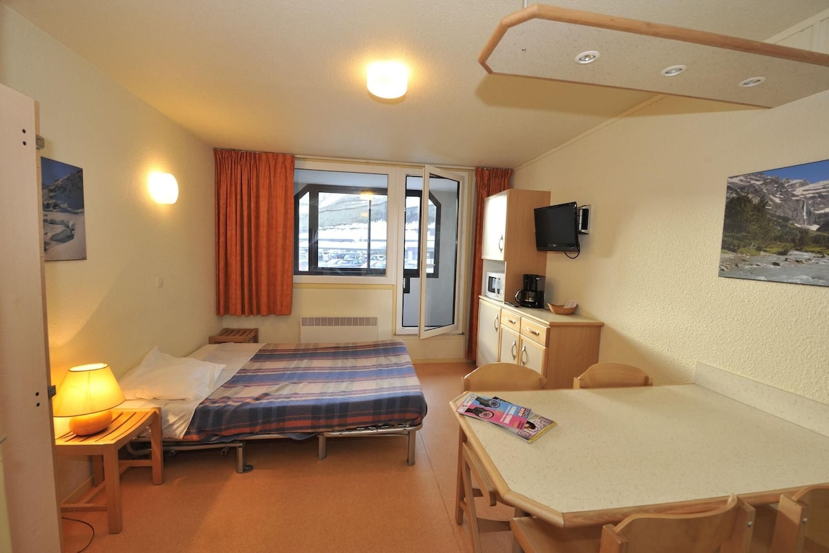 Een hotelkamer met twee bedden, een bureau, een stoel, een televisie en een raam met gordijnen.