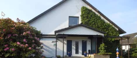 A two-story building with a white facade and a small porch area.