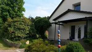 Een huis met een overdekte veranda, een stenen muur en een schommel met kleurrijke ballen.