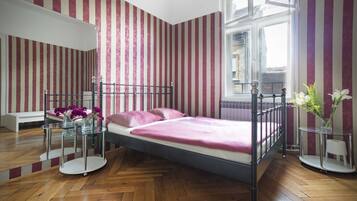 Una habitación con cama, una mesa de vidrio, un banco y una ventana.