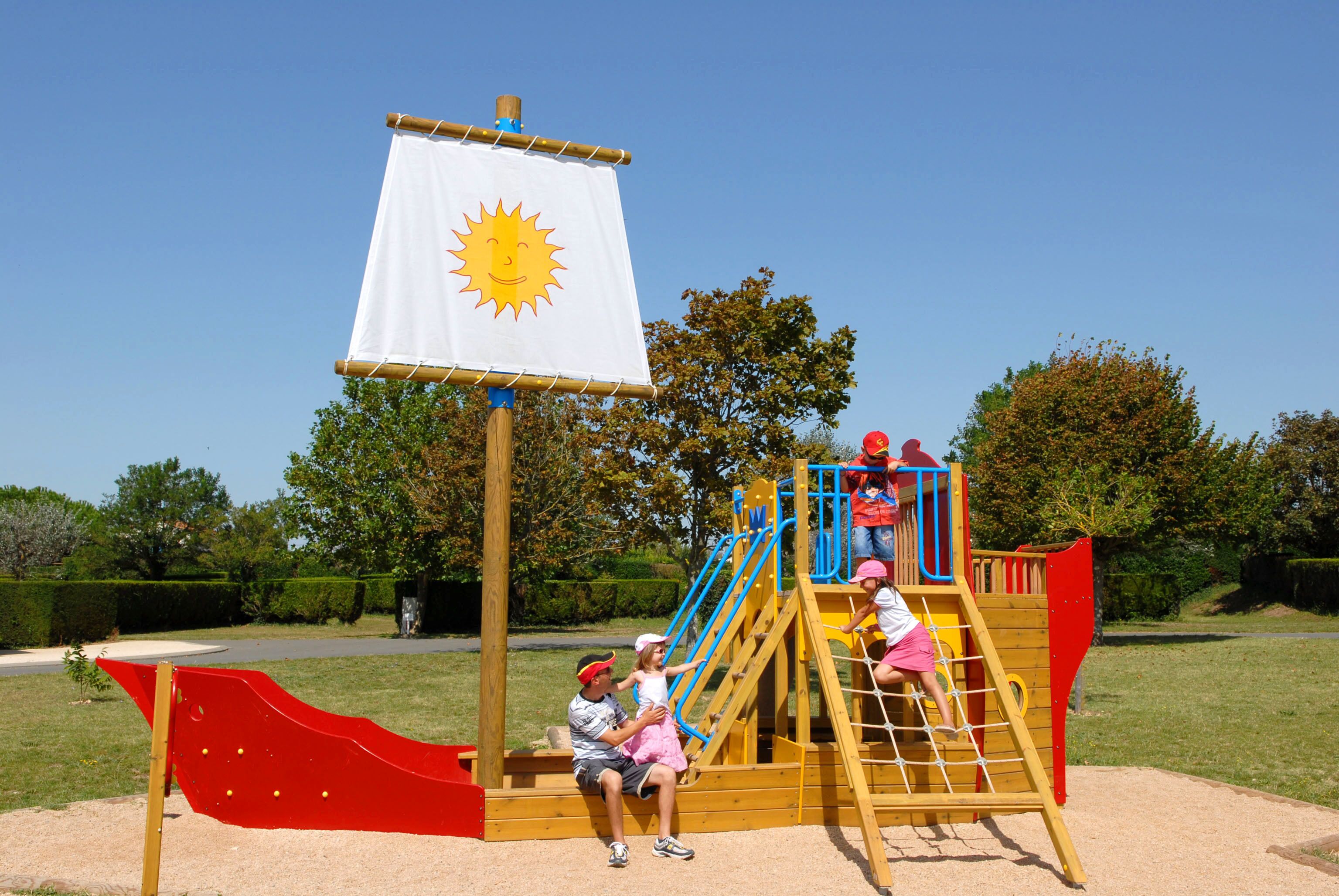 Une aire de jeux avec un toboggan, un filet d’escalade et un drapeau.