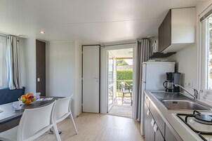 Une cuisine compacte avec un coin repas, une machine à café et une vue sur l’extérieur.