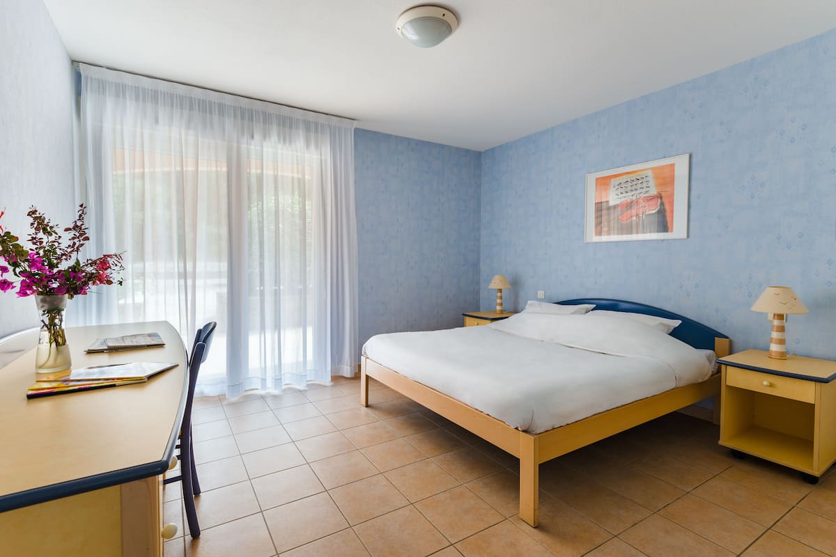 Ein Schlafzimmer mit einem Bett, Nachttischen, einem Schreibtisch und einem Stuhl.