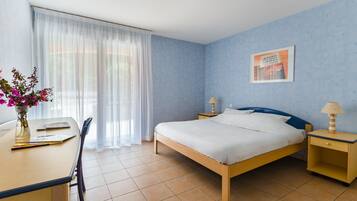 A bedroom with a bed, bedside tables, a desk, and a chair.