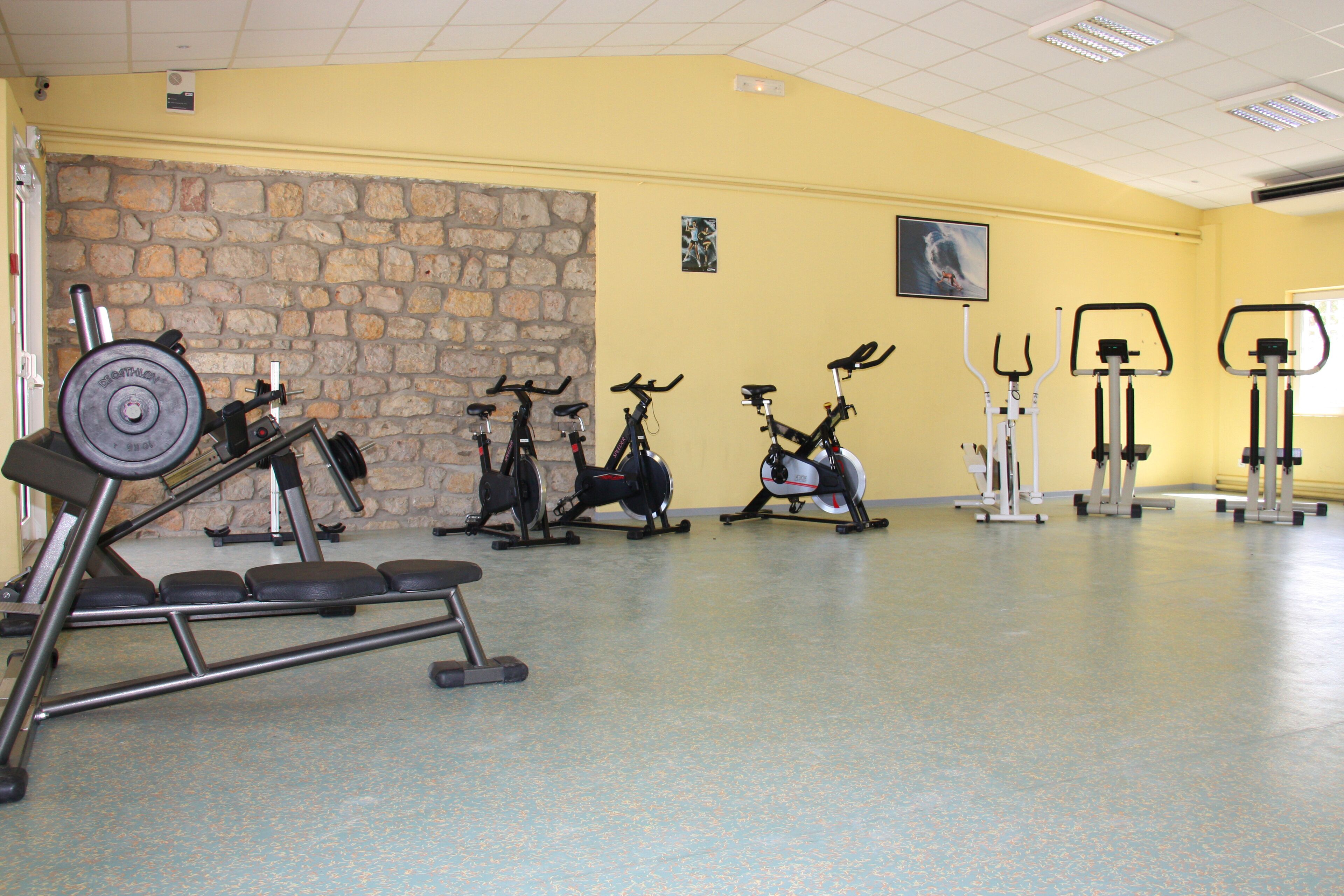 A gym with various exercise equipment, including treadmills, stationary bikes, and weight machines.