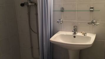 Une salle de bain avec une douche, un lavabo et un miroir.