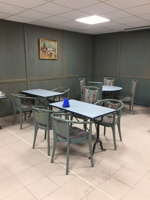 A conference room with tables and chairs, a painting on the wall, and a ceiling light. - Hotel De La Mare (Avrigny)